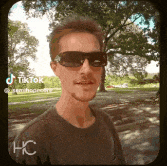 a man wearing sunglasses is standing in a park with trees in the background and the words tiktok semihopecore below him
