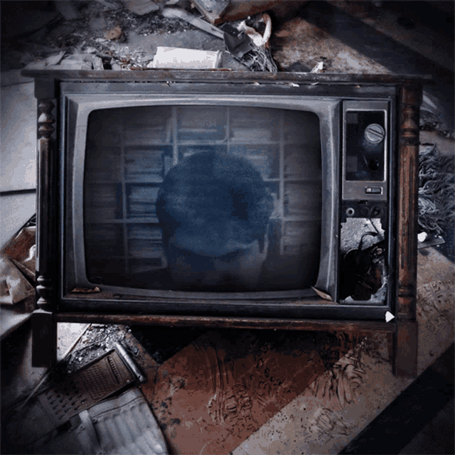 a broken television with a reflection of a person on the screen