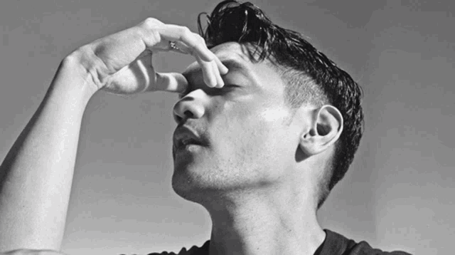 a black and white photo of a man covering his eyes with his hands