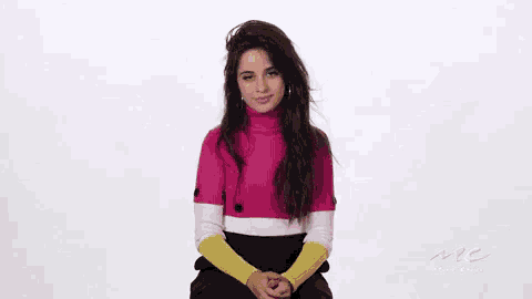 a woman is sitting on a chair with her eyes closed . she is wearing a pink sweater and yellow sleeves .