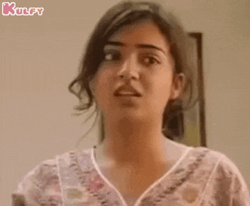 a woman is making a funny face while standing in front of a wall .