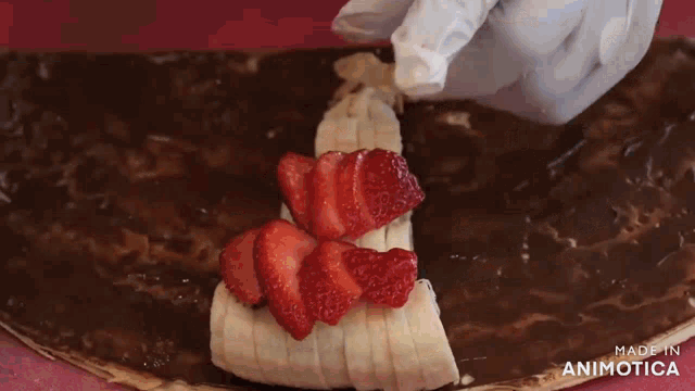 a person is making a dessert with strawberries and bananas and the words made in animotica on the bottom
