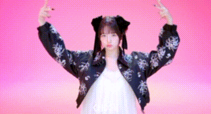 a woman in a white dress and a black jacket is making a peace sign with her arms in the air .