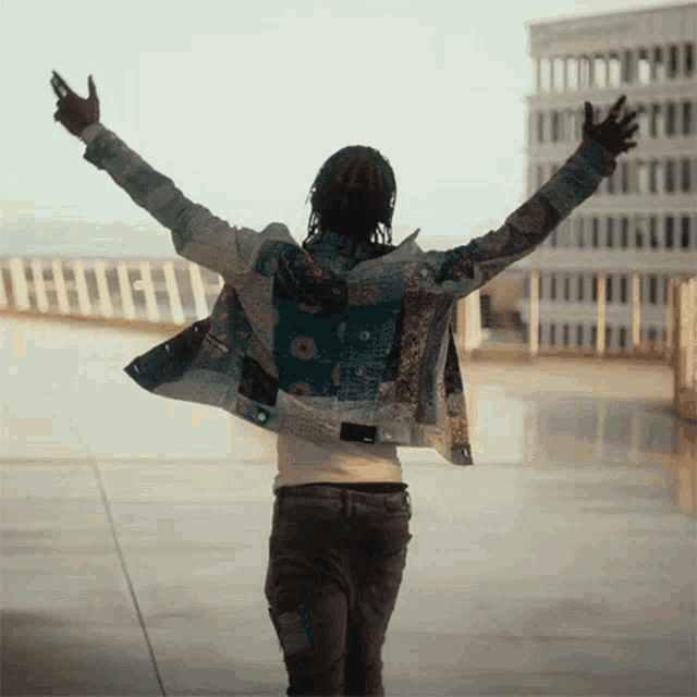 a man with his arms outstretched is wearing a jacket with a patchwork pattern
