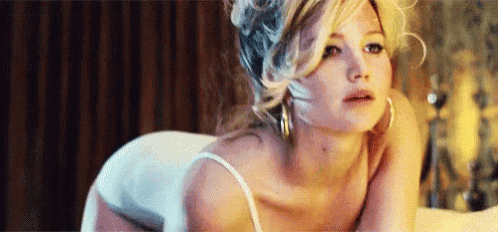 a woman is laying on her stomach on a bed in a white bra .
