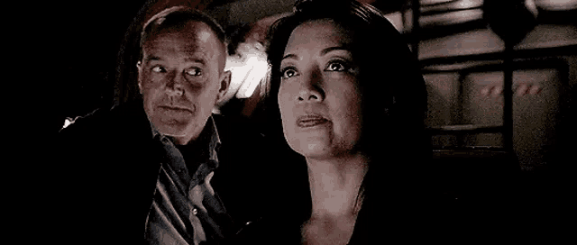 a man and a woman are standing next to each other in the dark .