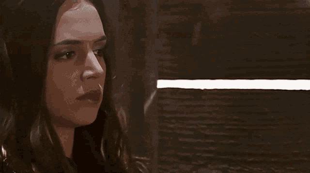 a woman is sitting in a dark room with a light shining through the walls