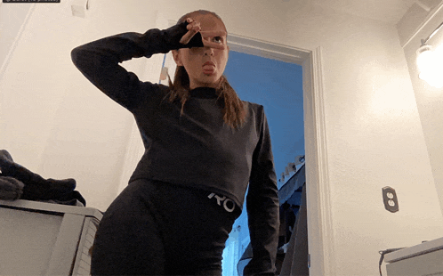 a woman wearing a black shirt with the letter o on the waistband