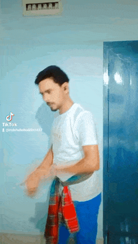 a man in a white shirt and blue shorts is standing in a room .