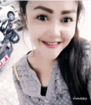 a woman is smiling and taking a selfie with a car in the background .