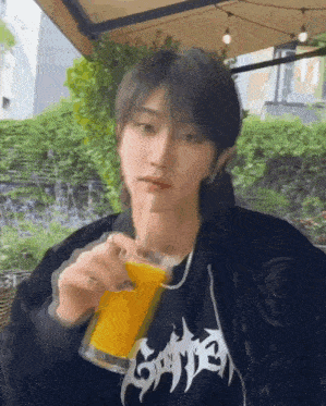 a young man is drinking a drink through a straw while sitting at a table .