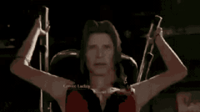 a man with long hair is standing on a cross with his arms outstretched .