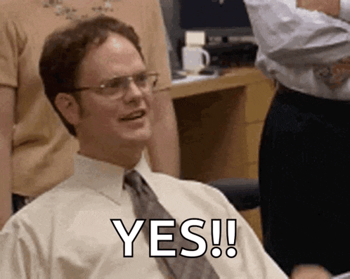 a man in a white shirt and tie is sitting in a chair and smiling while saying yes .