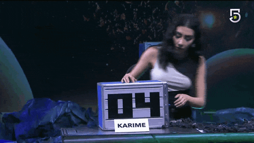 a woman sits in front of a box that says karime