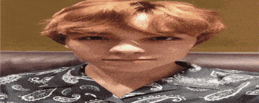 a young man with red hair is wearing a paisley shirt and making a funny face