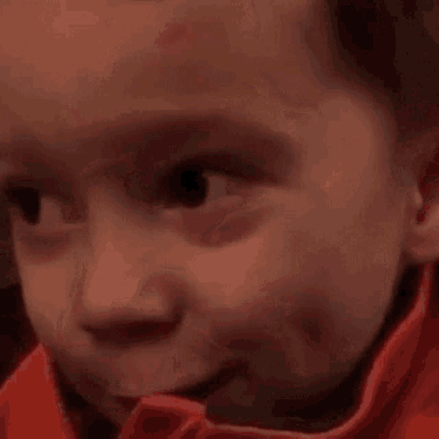 a close up of a child 's face with a red spot on his forehead and a smile .