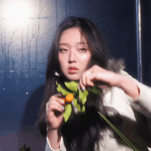 a woman with long hair is holding a flower in her hands .