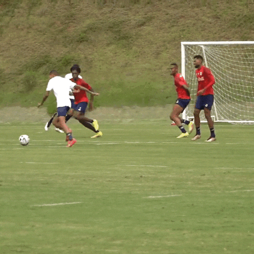 a soccer player wearing a red bulls shirt kicks the ball