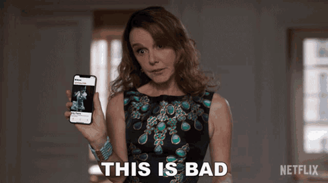a woman holding a cell phone with the words " this is bad " on the bottom