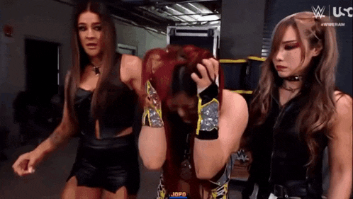 three female wrestlers are standing next to each other in a room .