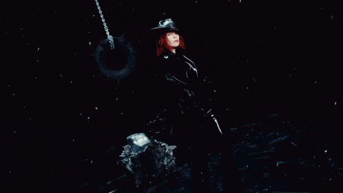 a woman in a cowboy hat is standing next to a tire