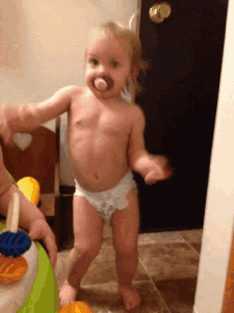 a baby in a diaper with a pacifier on his mouth