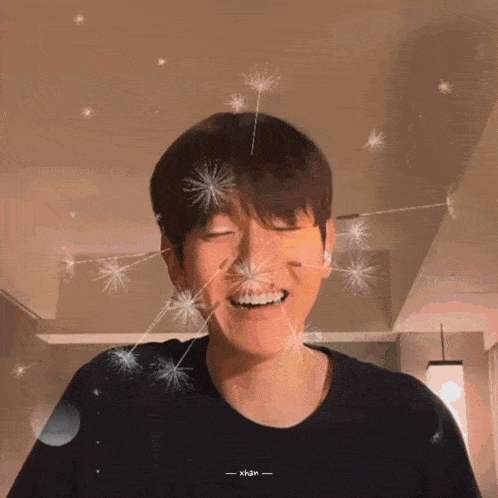 a man in a black shirt is smiling with sparklers around his head