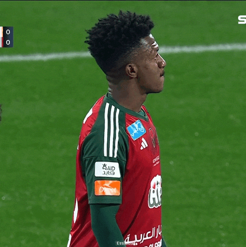 a soccer player wears a red and green jersey with the word aid on the sleeve