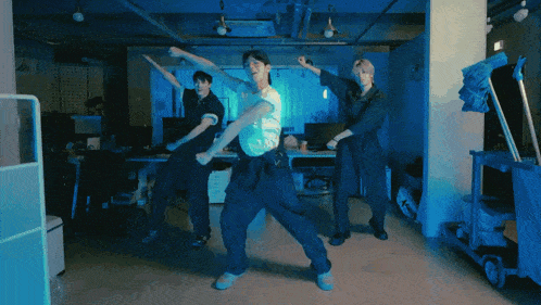 a group of young men are dancing in a room with a mop in the background