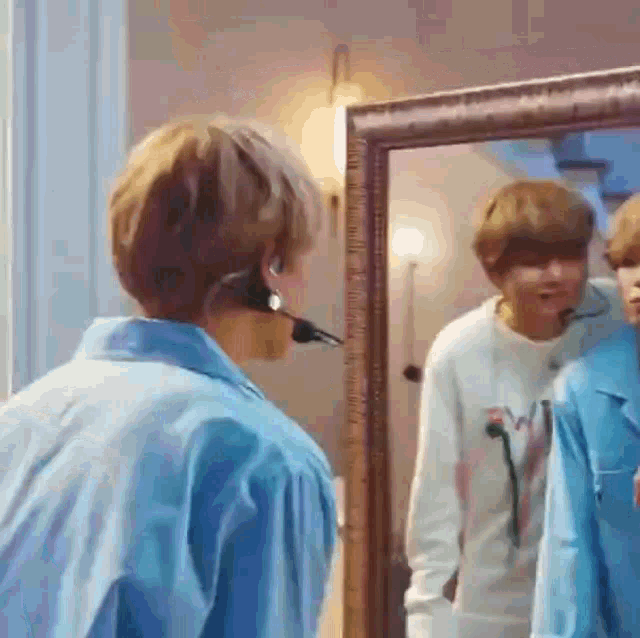 a man wearing a headset is standing in front of a mirror .