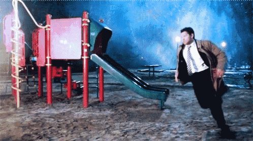 a man in a suit and tie is running towards a slide