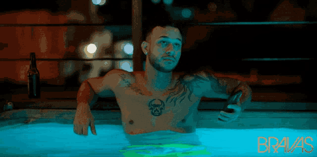 a shirtless man with a tattoo on his chest is sitting in a hot tub