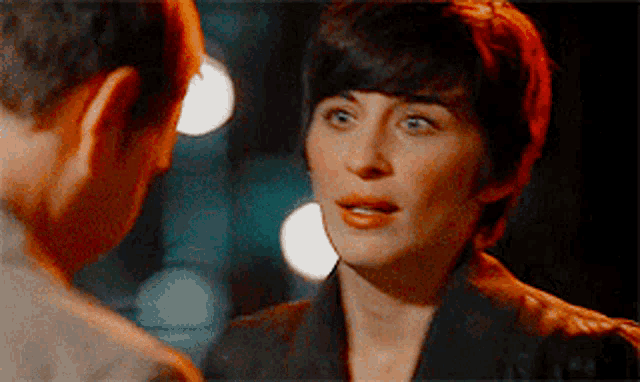 a man and a woman are looking at each other and the woman has short hair