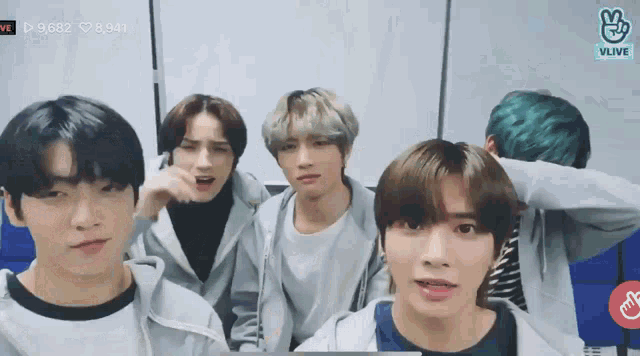 a group of young men are standing next to each other in a room and looking at the camera .