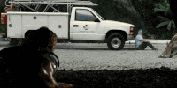 a man is sitting on the ground next to a white truck