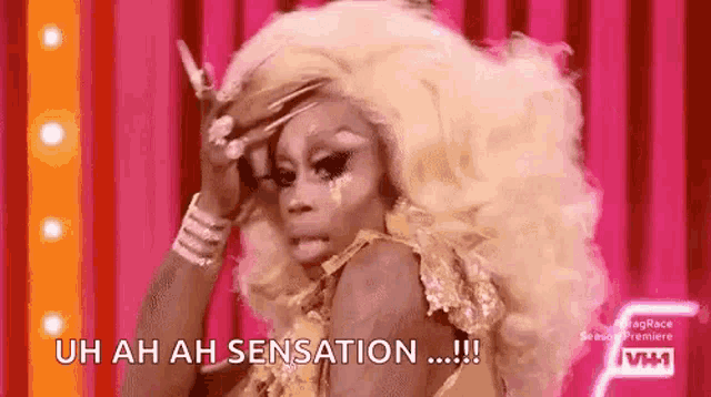 a drag queen with blonde hair is making a funny face on a pink background .