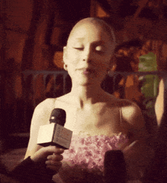 a woman in a pink dress is talking into a microphone that says ' hollywood ' on it