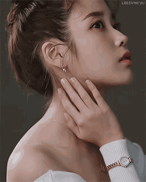 a close up of a woman 's face with a watch on her wrist