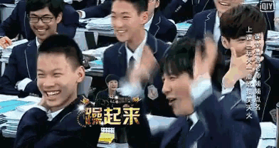 a group of young men in suits and ties are sitting in a classroom with chinese writing on the wall .