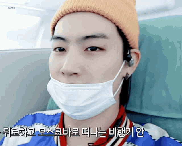a man wearing a yellow beanie and a white face mask with foreign writing on the bottom