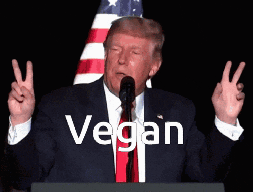 donald trump giving a peace sign in front of an american flag with the word vegan written below him