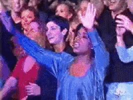 a woman in a blue shirt is standing in a crowd of people