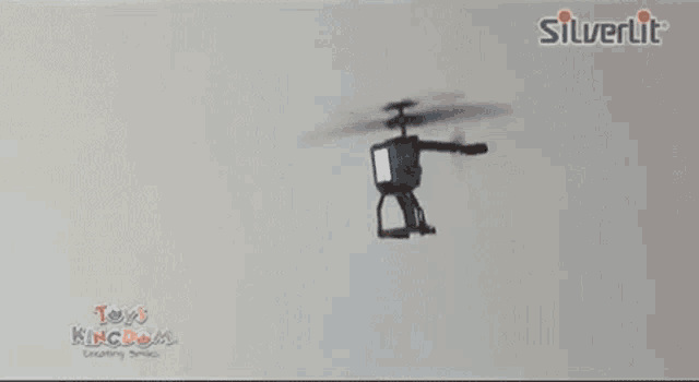 a person is holding a toy helicopter in front of a silverlit logo