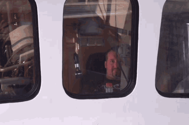 a man wearing a shirt that says tnc is looking out a window