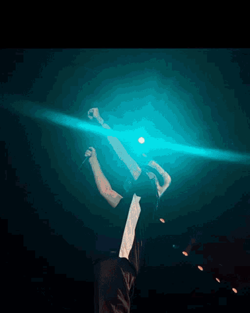a person is standing on a stage with a microphone in their hand and a blue light behind them