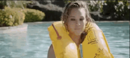 a woman is wearing a life jacket in a pool .