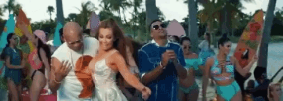 a man and a woman are dancing on a beach with a crowd of people .