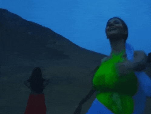 a woman in a green tank top is dancing in the dark