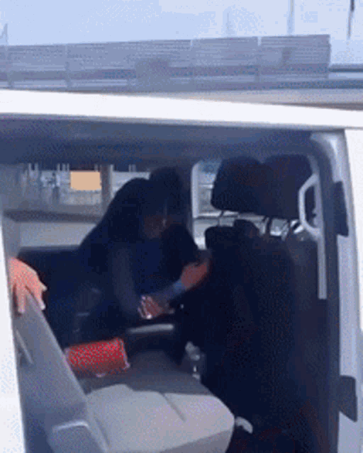 a man and woman are sitting in the back seat of a white van