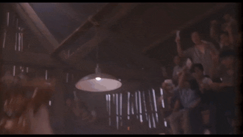 a woman in a bikini is being kicked in the face by a man in a boxing ring in front of a crowd .